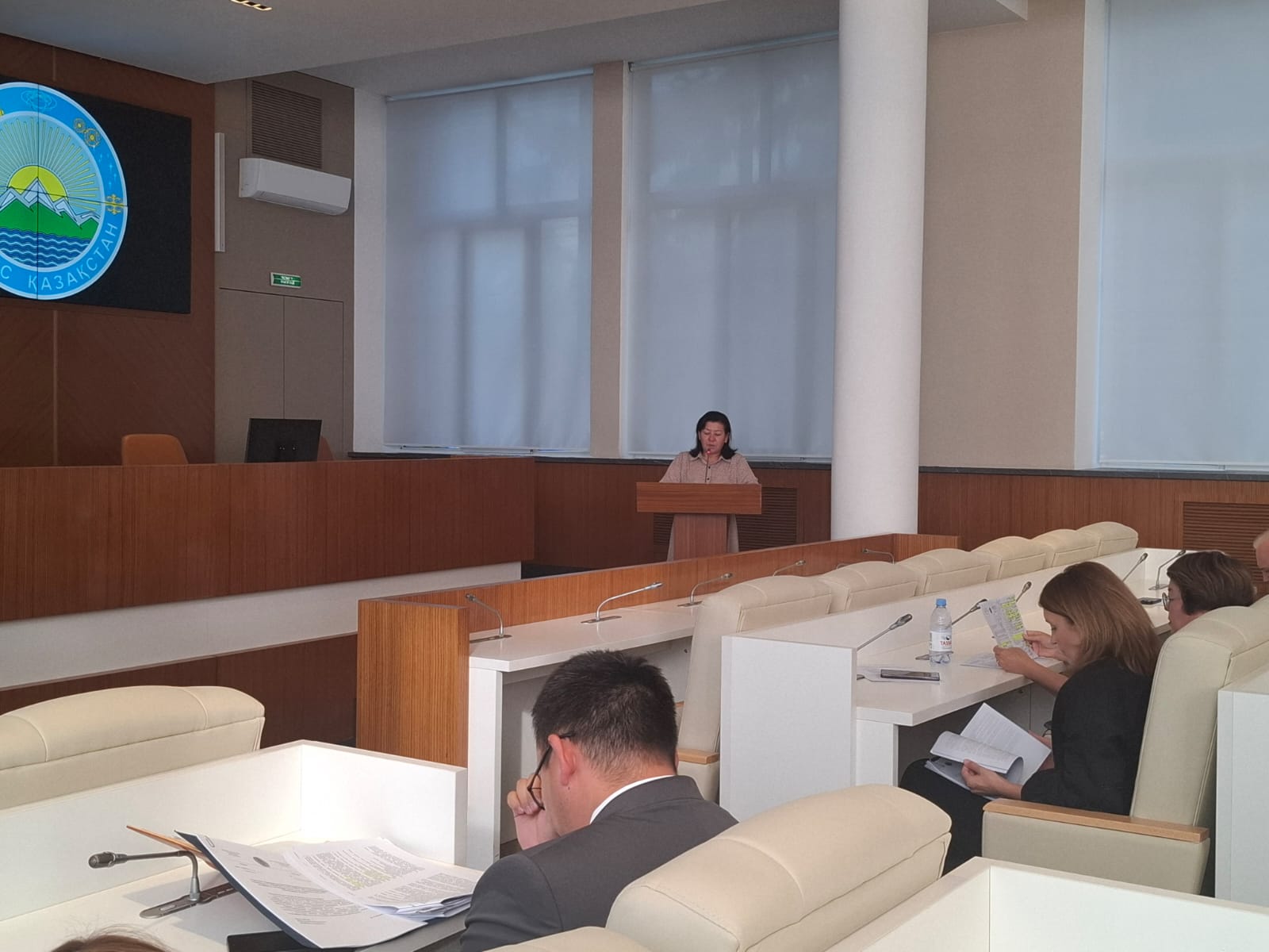 Суретте депутаттар алдында құрылыс, сәулет және қала құрылысы басқармасы басшысының орынбасары А. К. Қайрақанова сөз сөйлейді.