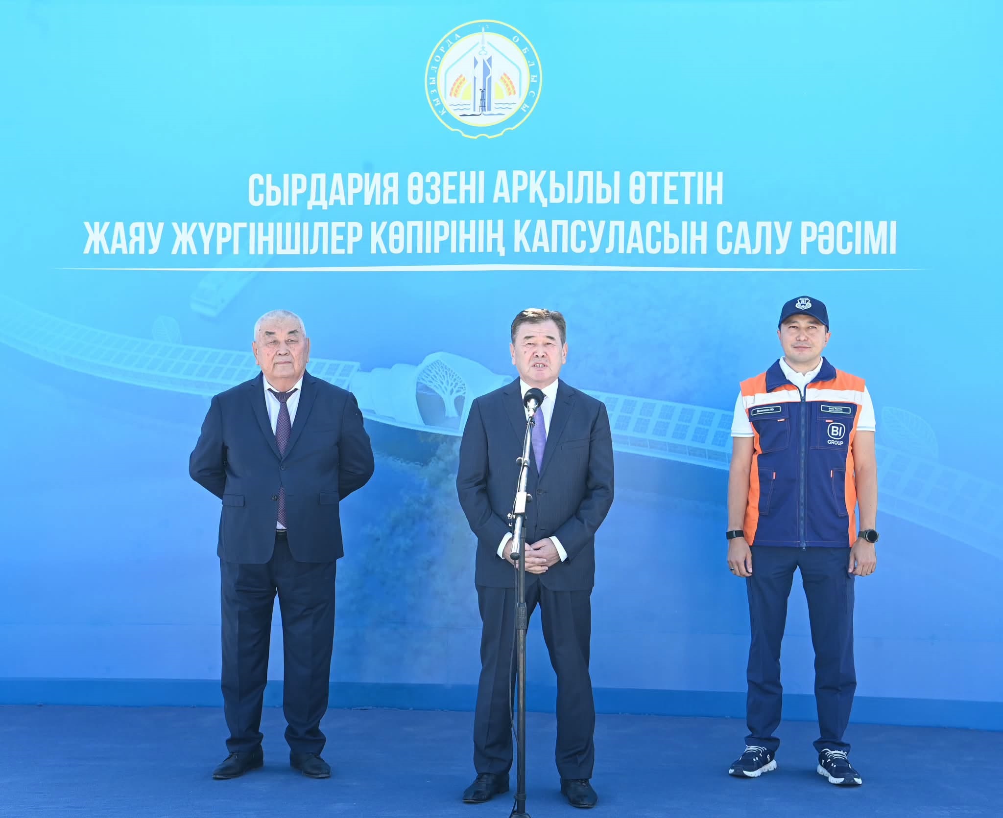 Сырдария өзеніне жаяу жүргіншілер көпірінің капсуласын салу рәсіміндегі үш ер адам.