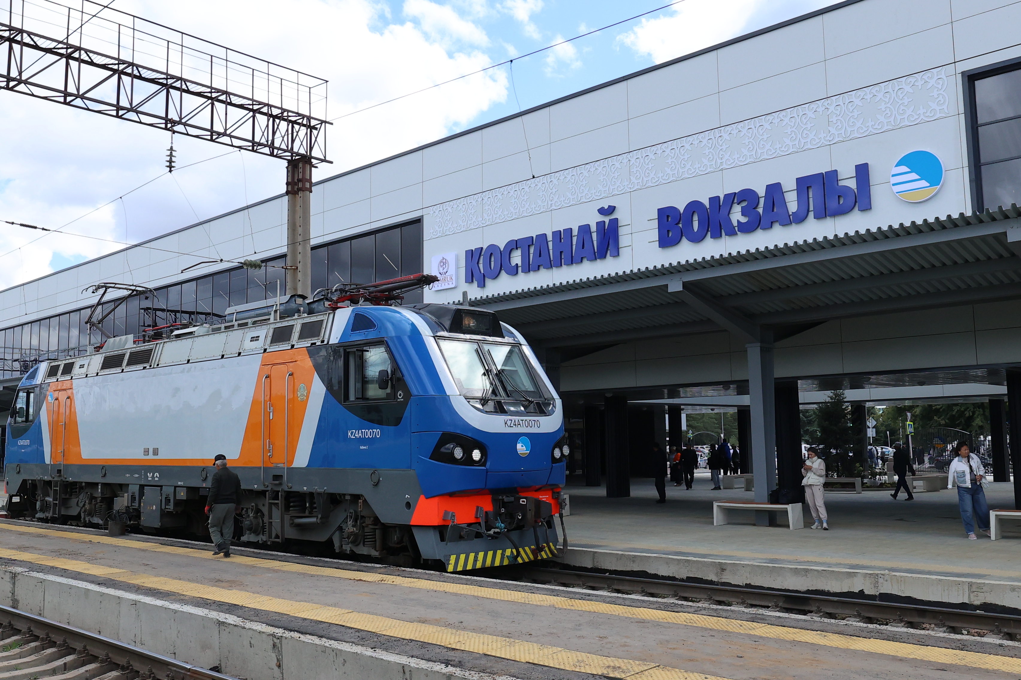 Вокзал платформасының жанындағы теміржол жолындағы заманауи электровоз.