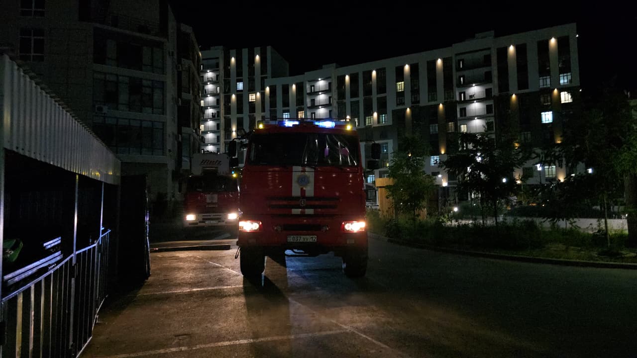 Түнгі уақытта тұрғын үйлердің алдында тұрған өрт сөндіру көлігі.