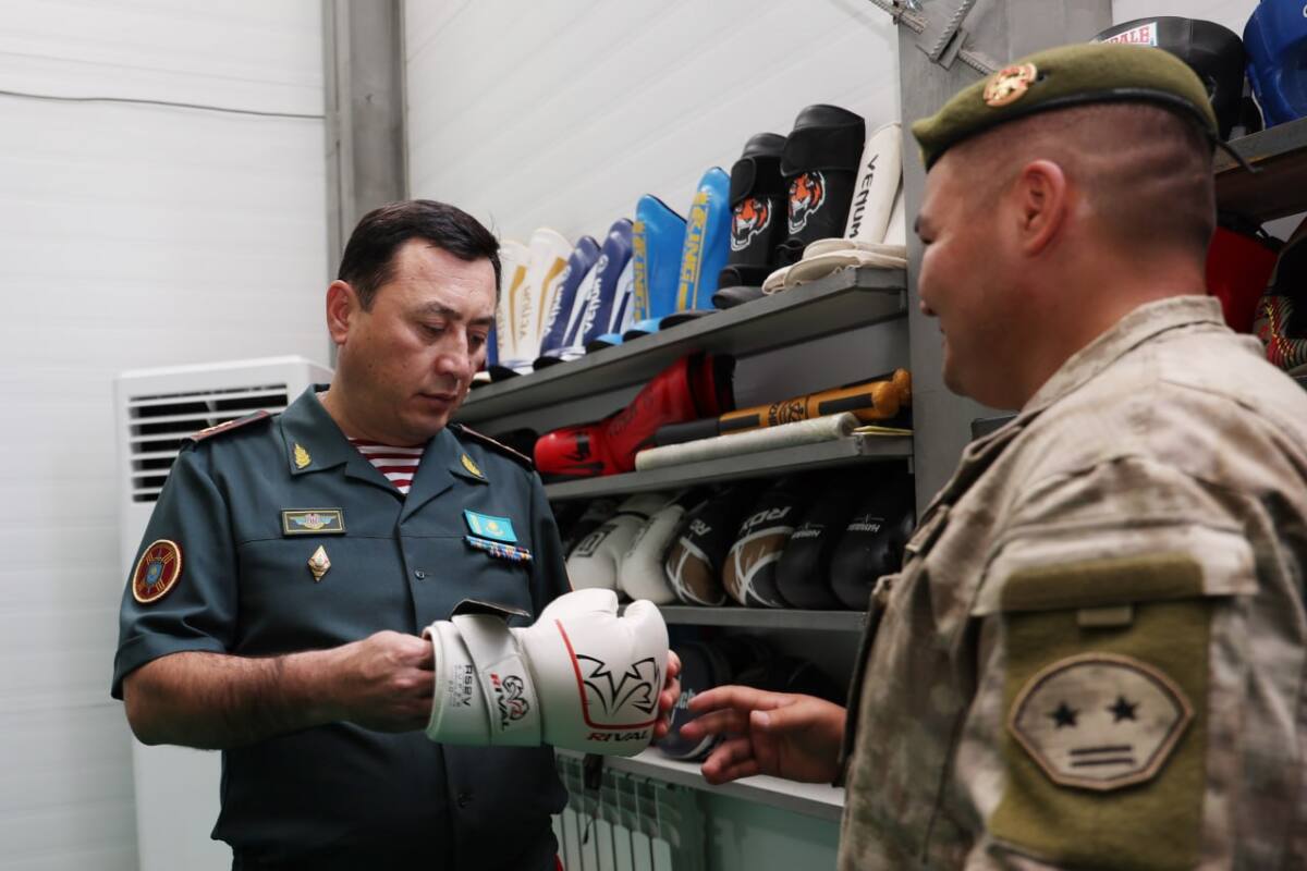Ұлттық ұланның Бас қолбасшысы Аңсаған Балтабеков пен сарбаз бокс қолғаптары тұрған сөренің алдында сөйлесіп тұр.