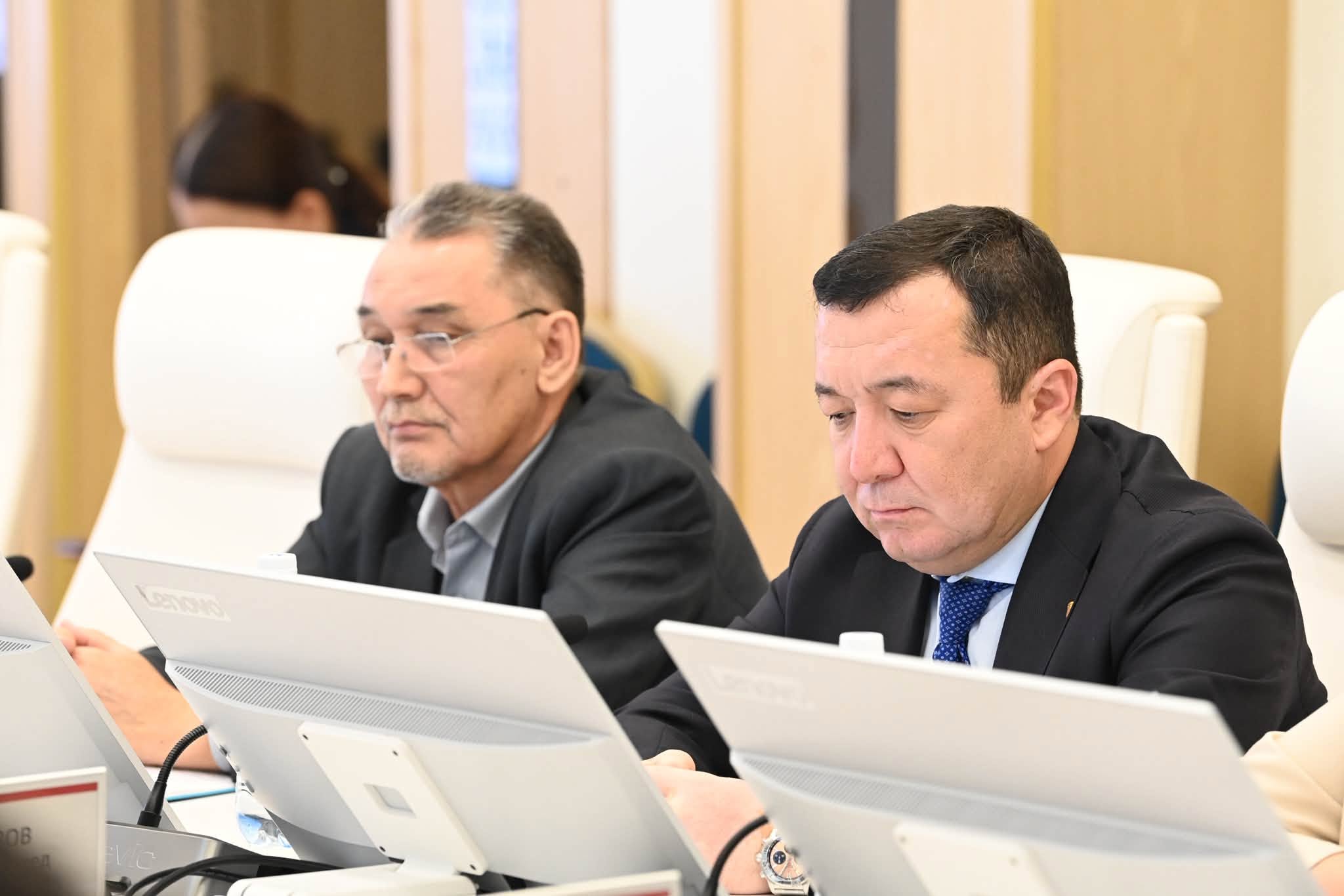 Компьютерлердің алдында отырған екі ер адам.