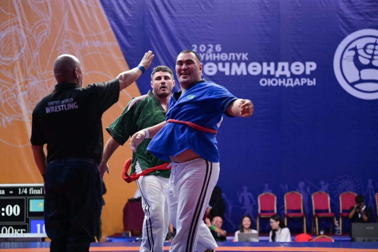 Күрес жарысындағы спортшылар мен төреші.