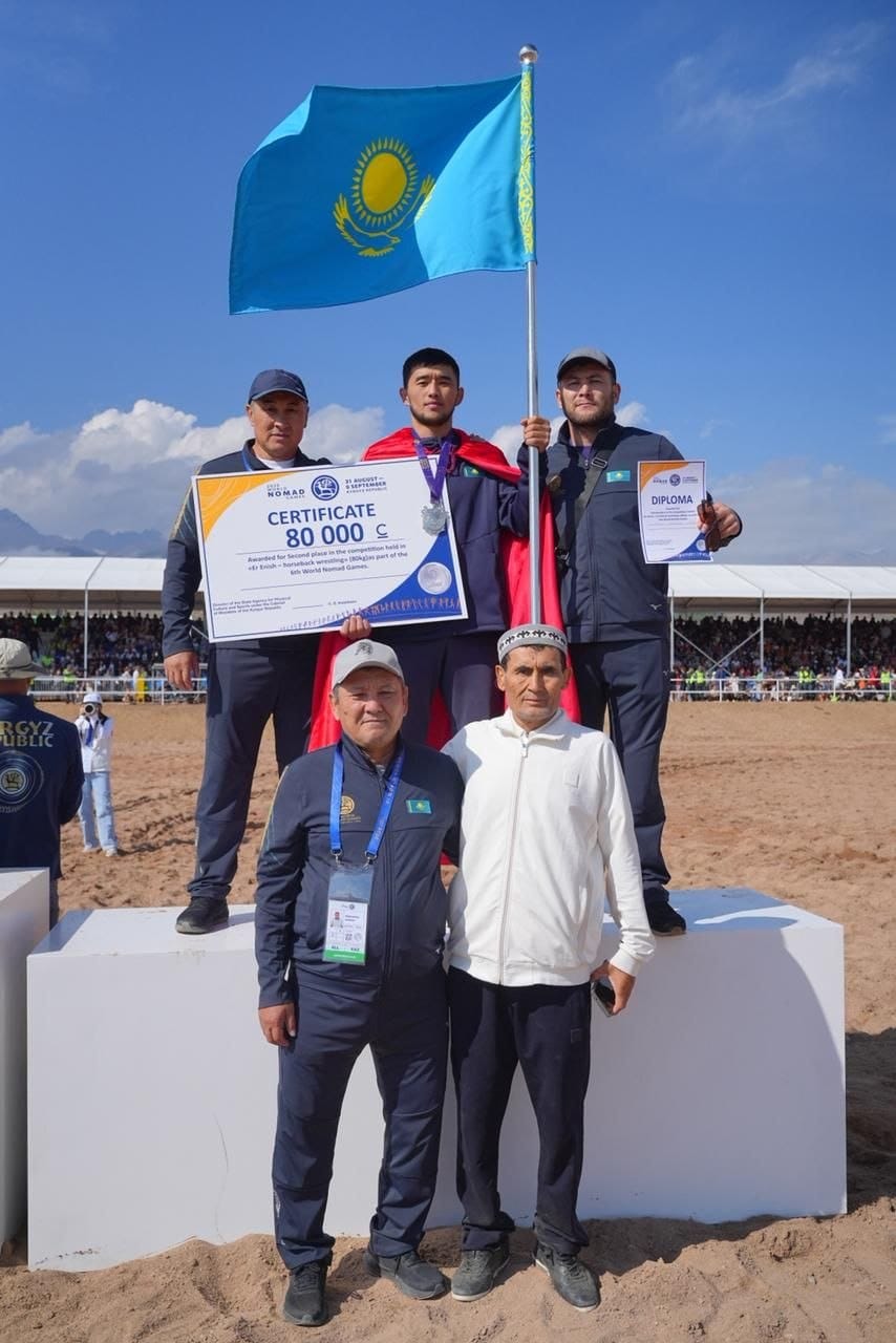 Қазақстан туымен және жүлделерімен тұғырда тұрған спортшылар мен жаттықтырушылар.
