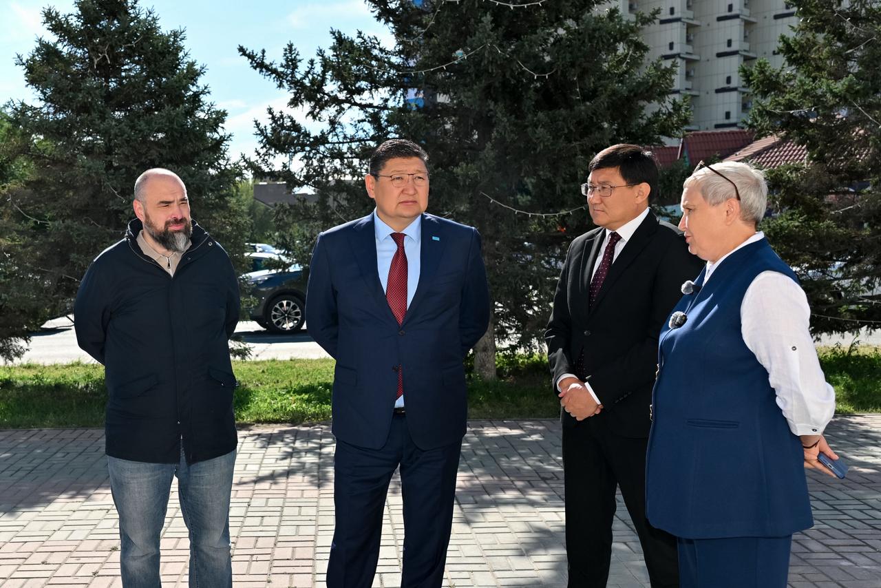 Сыртқы жерде тұрған төрт адамның тобы.