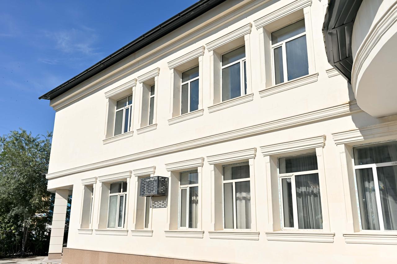 Ақ түсті екі қабатты заманауи ғимараттың сыртқы көрінісі.