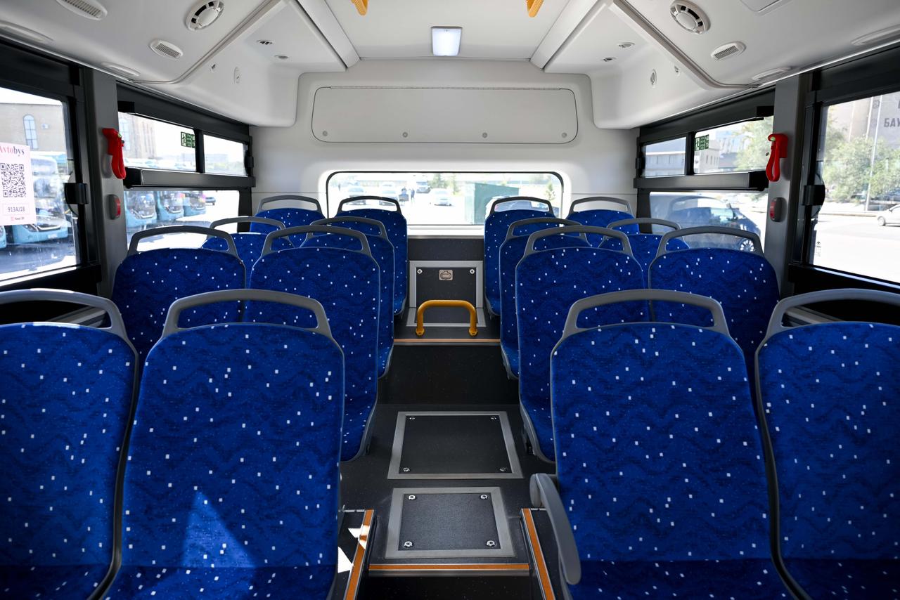 Көк түсті орындықтары бар автобустың ішкі көрінісі.