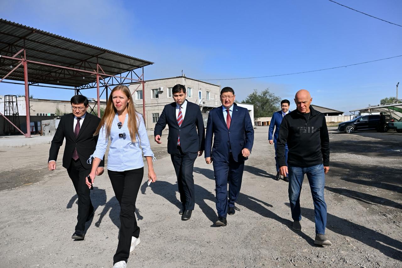 Іскер киімдегі адамдар тобы сыртқы алаңда жүріп келе жатыр.