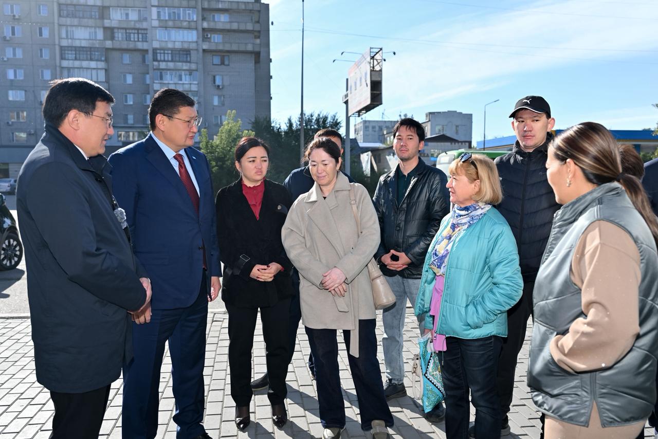 Көшедегі жиналыста тұрған адамдар тобы.