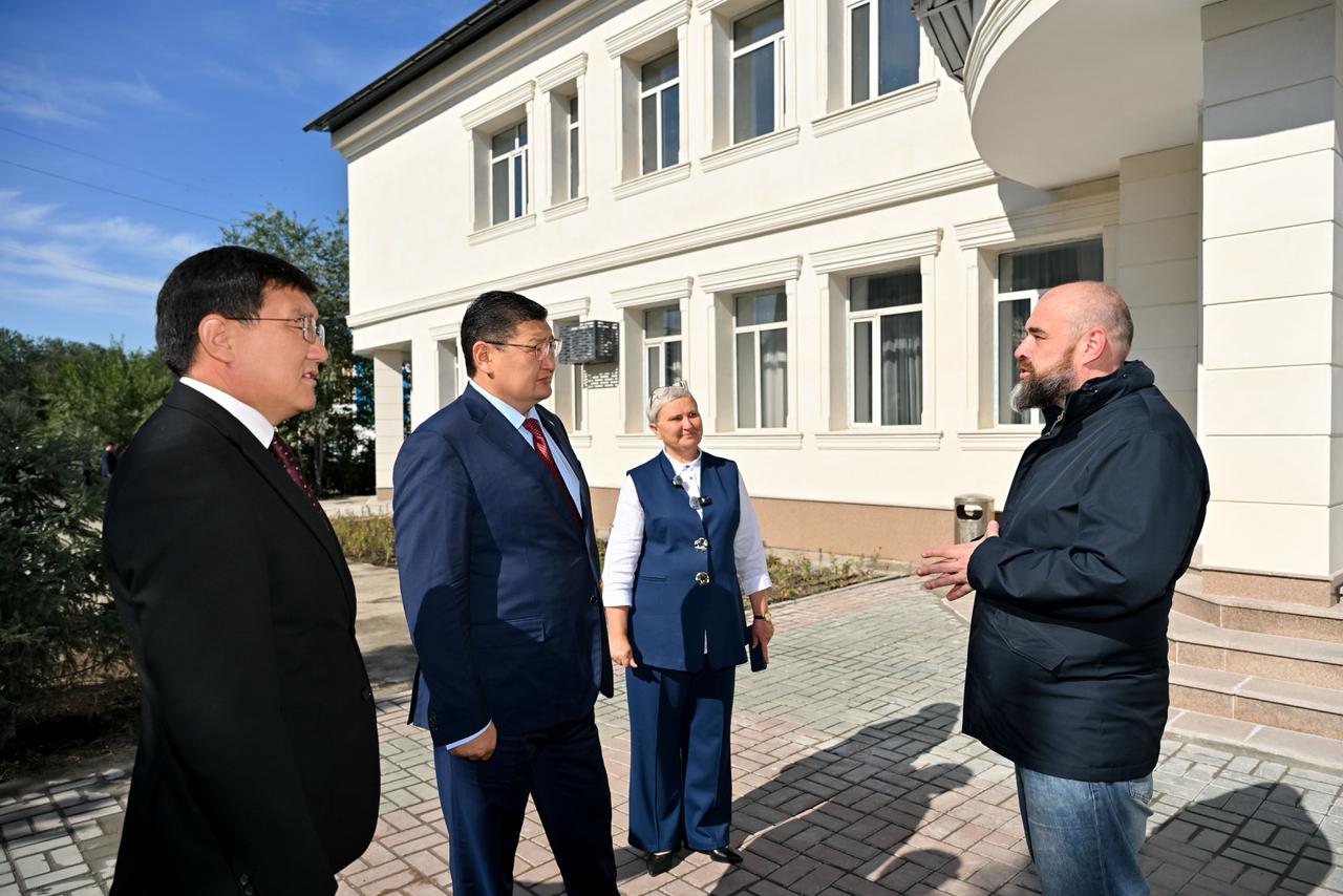 Ғимарат алдында тұрған төрт адамның әңгімелесуі.
