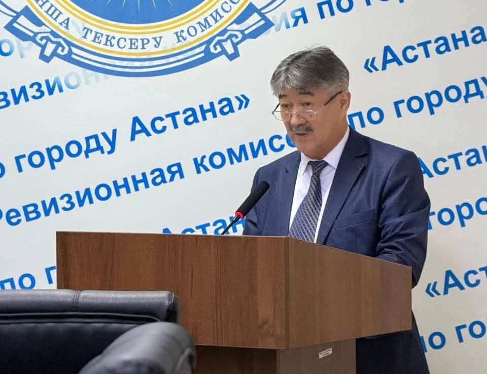 Костюм киген ер адам трибунада сөйлеп тұр. Артында Астана қаласының тексеру комиссиясының жазуы бар фон.