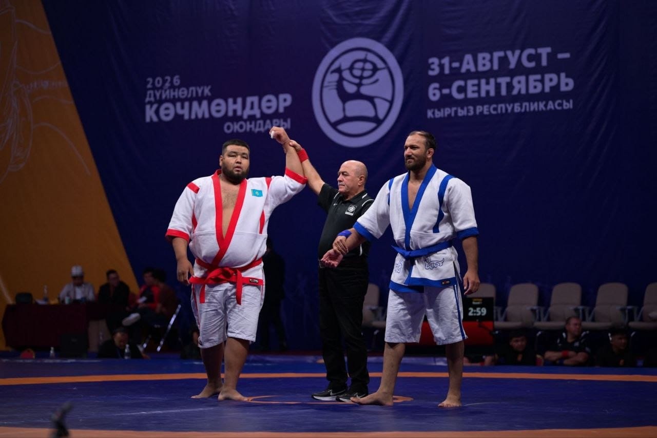Күрес жарысының төрешісі спортшының қолын көтеріп, жеңімпазды жариялап жатыр.