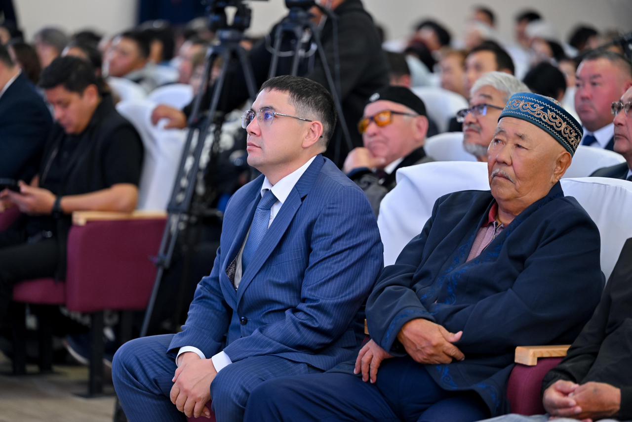 Жиынға жиналған адамдар: костюм киген жас ер адам мен тақия киген қарт кісі.
