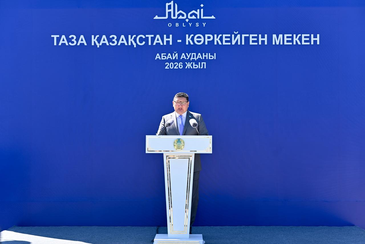 Көк фонды және «Таза Қазақстан» жазуы бар трибунада сөйлеп тұрған ер адам.