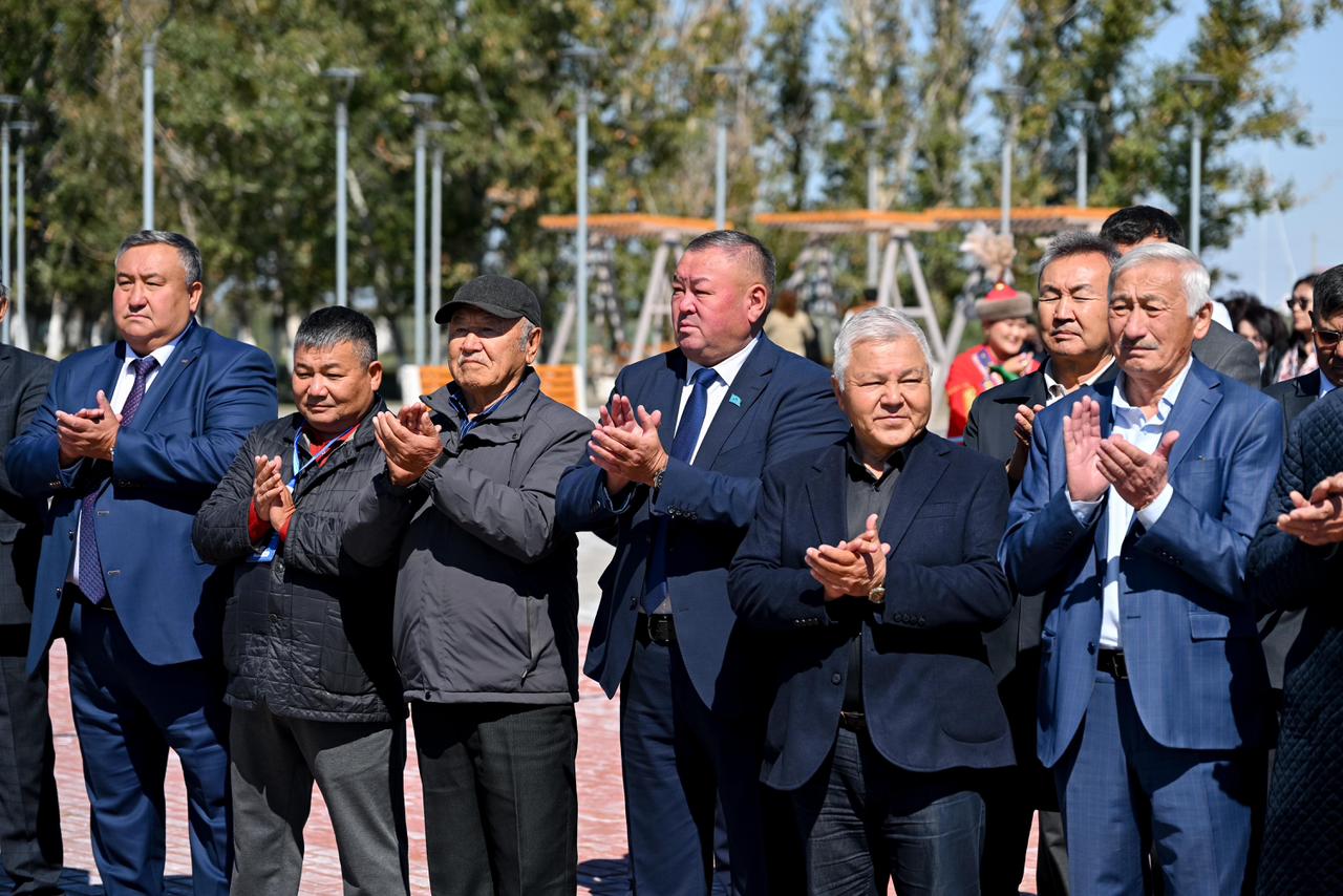Шашақтап тұрған, қол шапалақтап тұрған костюм киген ер адамдар тобы.