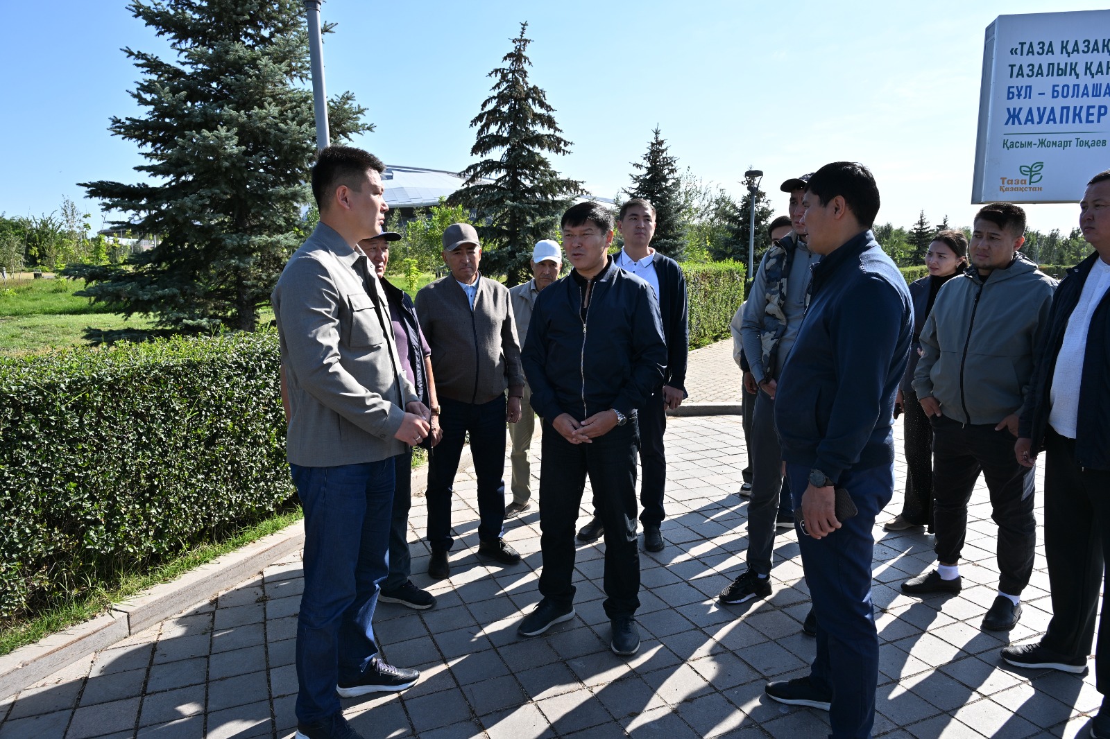 Ашық ауада жиналған ерлер тобының әңгімелесуі.
