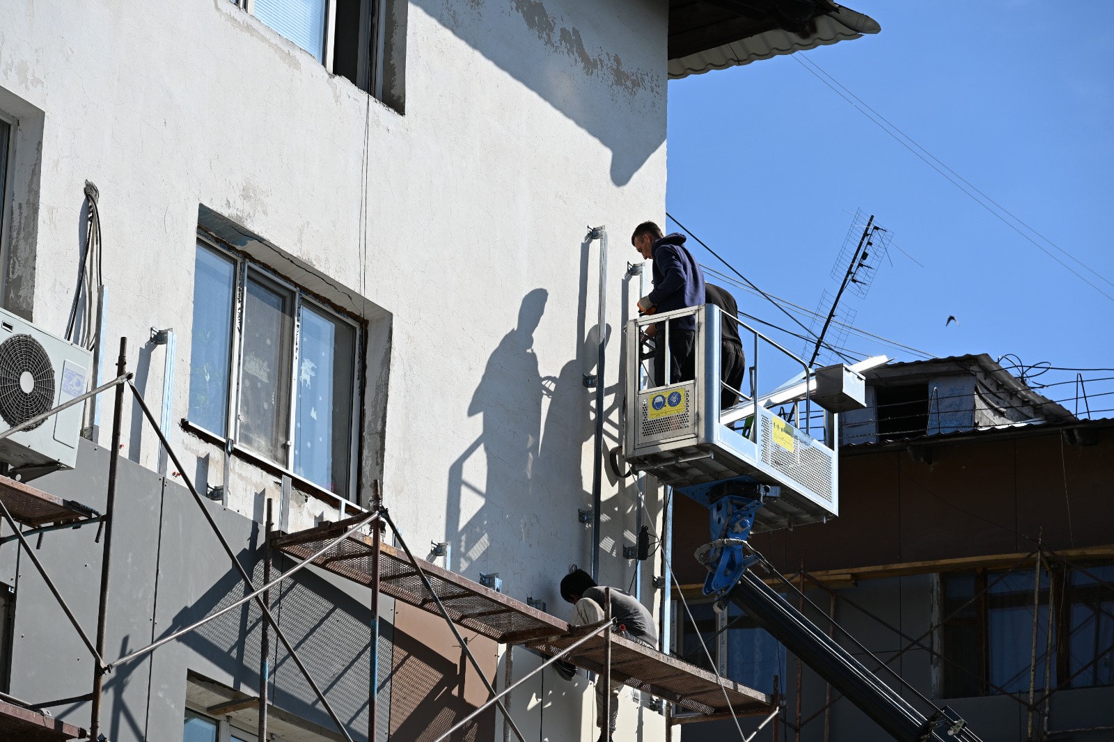 Жұмысшылардың ғимарат сыртын жөндеу жұмыстарын жүргізуі.