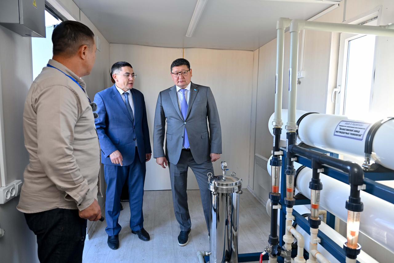 Костюм киген екі ер адам мен маман су lọcқы қондырғыны қарап тұр.